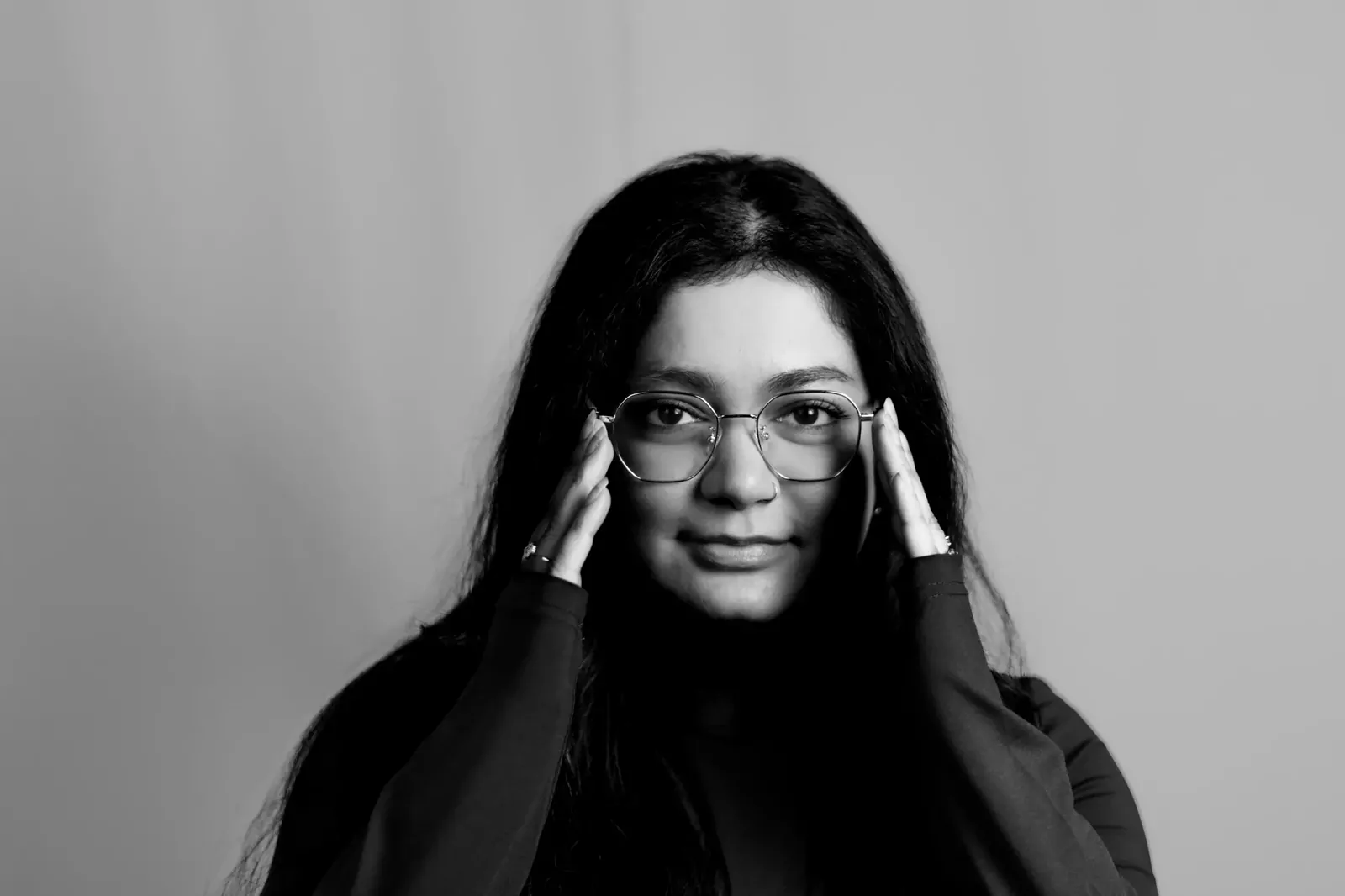 Black and white corporate portrait of a woman adjusting her glasses