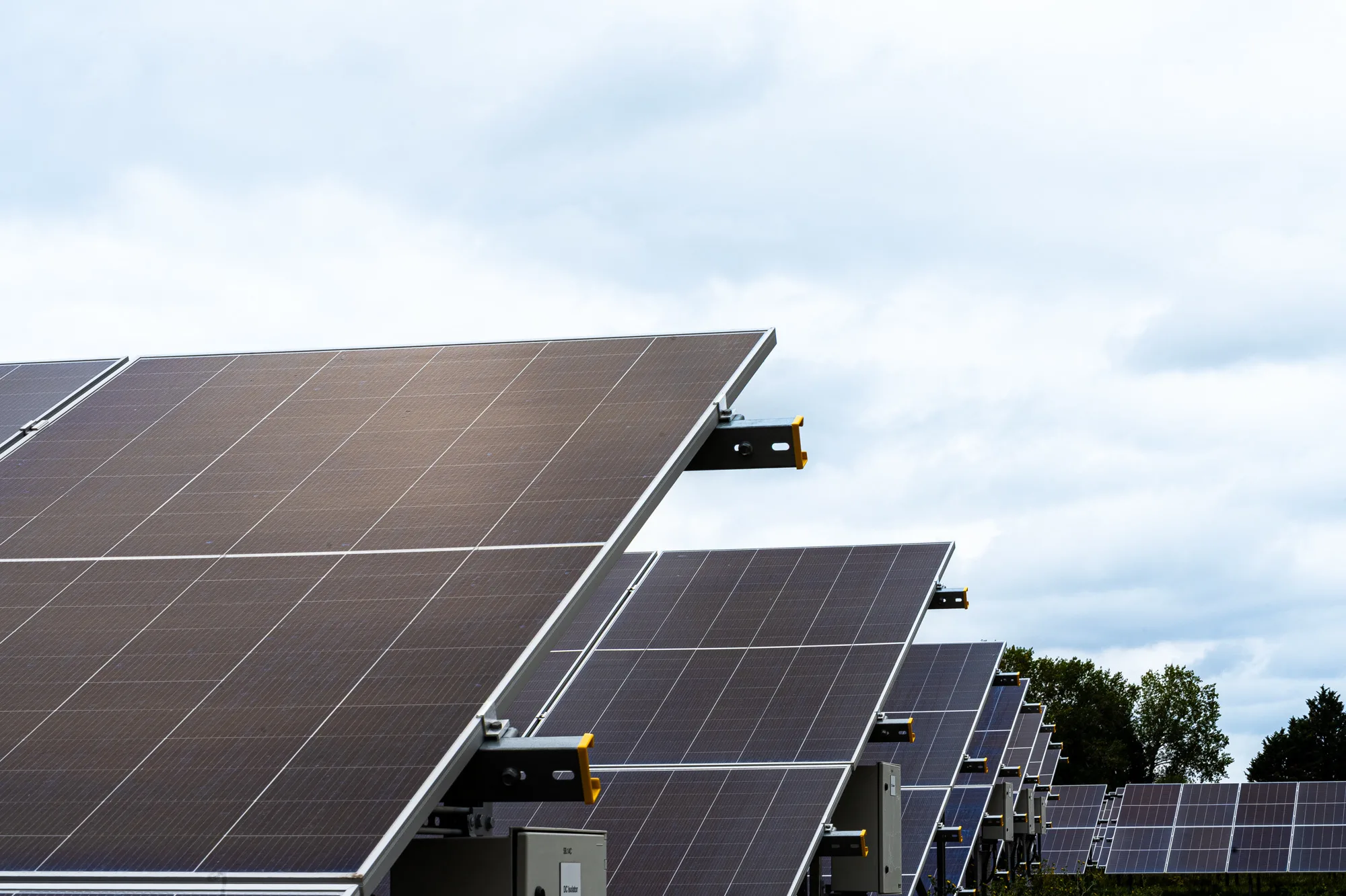 Solar panel array viewed from below against a cloudy sky