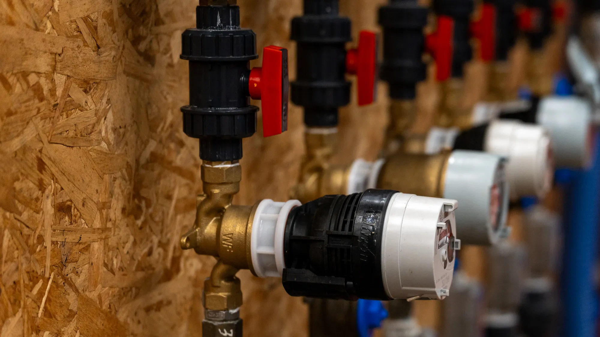 Row of ball valves and pipe fittings on industrial pipework
