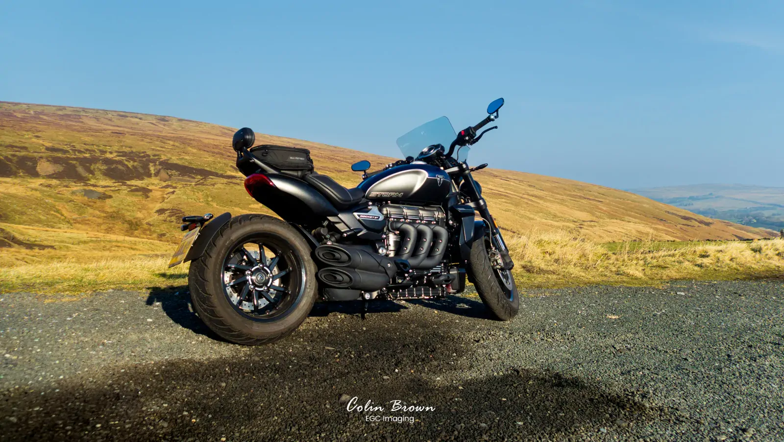 Motorcycle parked on a hillside road with rolling moorland behind