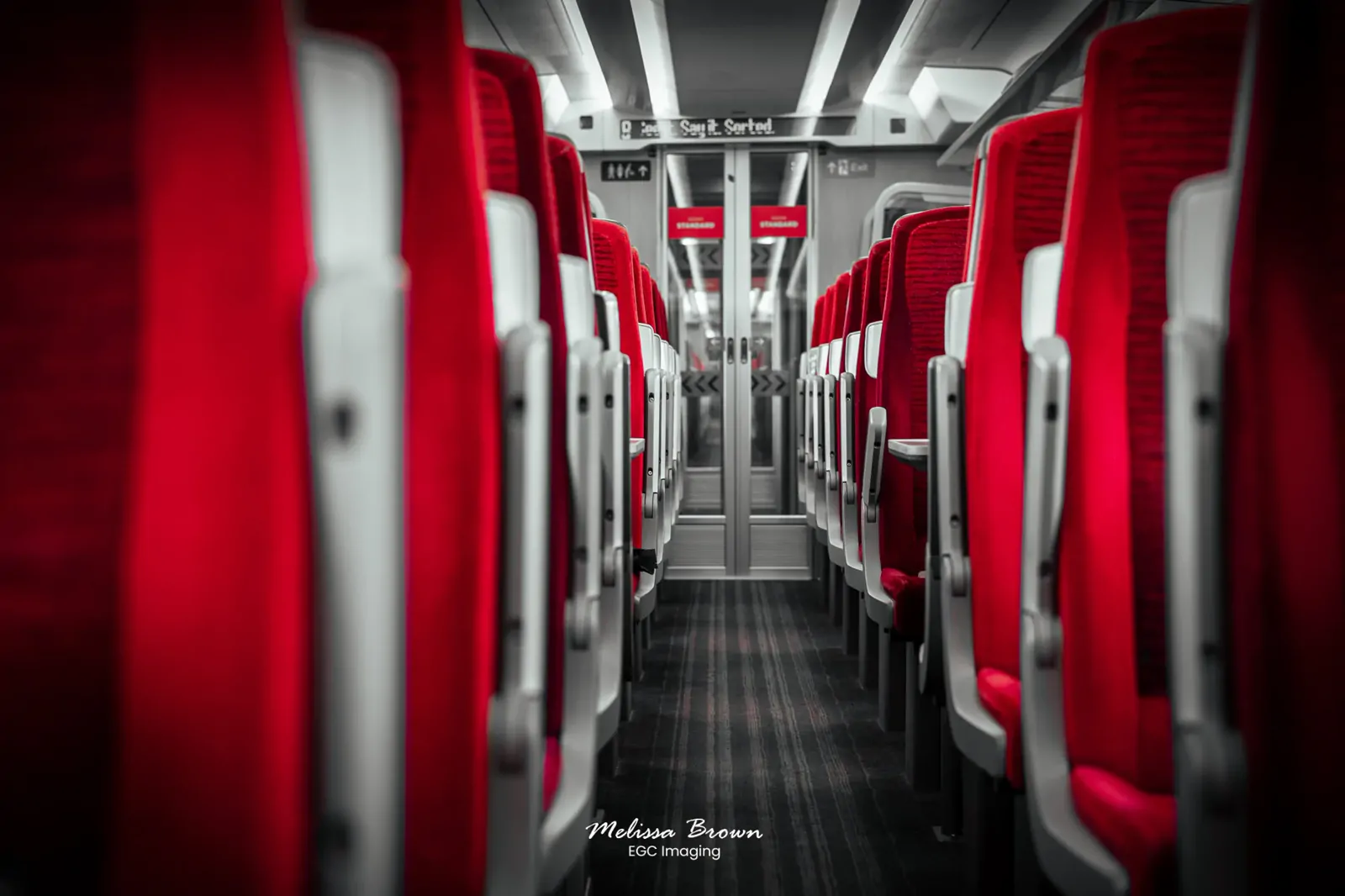 Rows of red train seats viewed down the aisle of an empty carriage