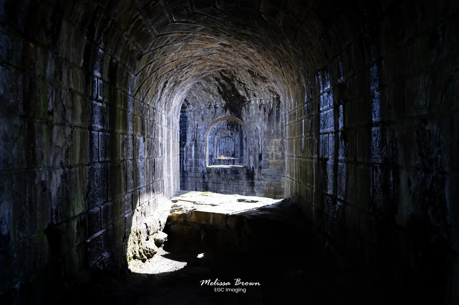 Sunlit stone archways inside a ruined vaulted passage